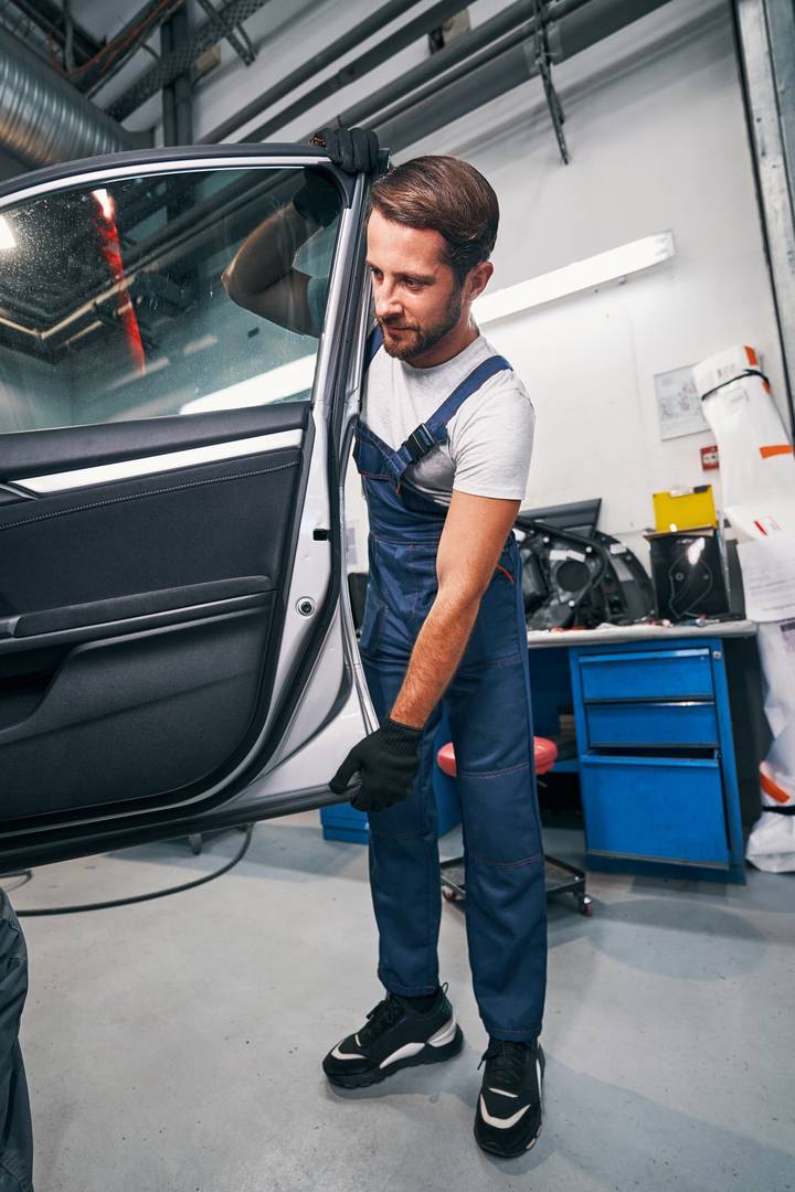 Mechanic taking off a door of automobile