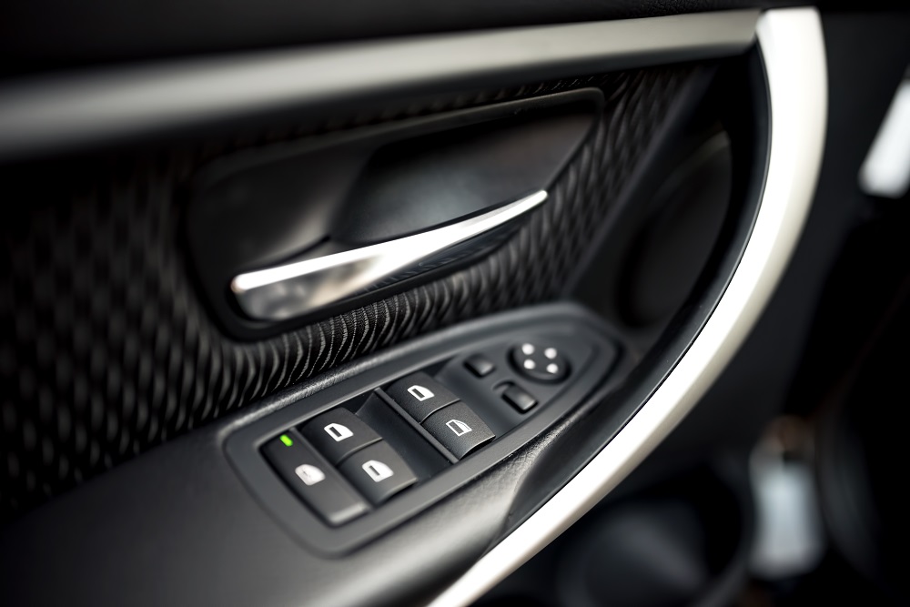 car interior details of door handle with windows controls and adjustments. Car window controls and details